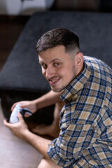 A man sits comfortably on a couch, holding a game controller