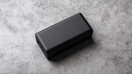 Modern Black Power Bank on Textured Concrete Surface in Soft Light