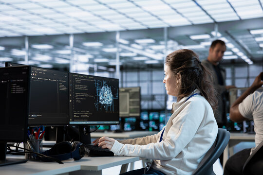 Engineer doing job shift in AI server hub used for processing vast amounts of data. Artificial intelligence programmer at work in data center, sitting at PC desk, typing on keyboard