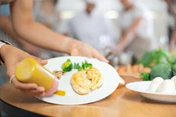 Womens hands, prepare, decorate tender baked chicken fillet with hot sauce. Group lesson cooking courses. Close-up