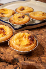 Portugal's traditional sweet dessert Pastel de nata egg custard tart pastry in cup close up on wooden background