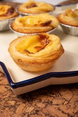 Portugal's traditional sweet dessert Pastel de nata egg custard tart pastry in cup close up on wooden background
