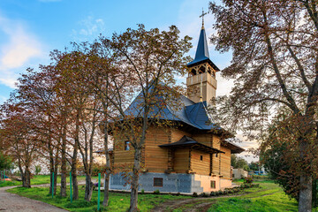 Rustic wooden church surrounded by autumn trees at sunset