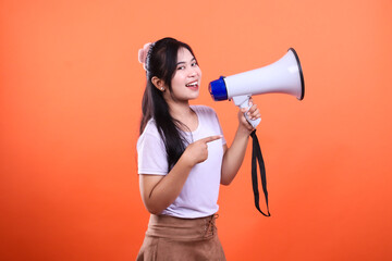 A woman with long dark hair holding a megaphone against an orange background