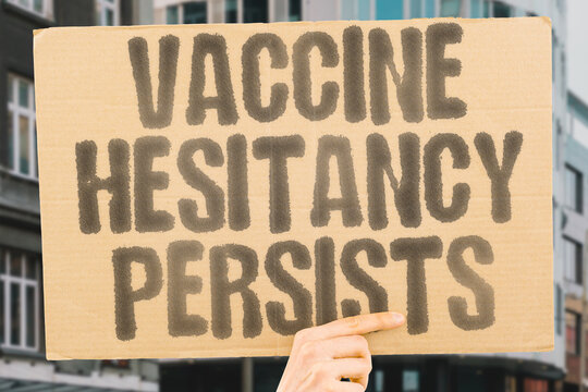 "Vaccine hesitancy persists" on worn cardboard. Highlights continued reluctance towards immunizations. SKEPTICISM. DOUBT. RESISTANCE. FEAR. MISINFORMATION. IMMUNIZATION. PREVENTION