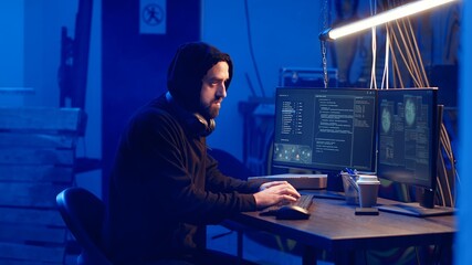 Hooded hacker creating pirating crack for software and video game releases in bunker. Rogue programmer getting past anti tamper measures implemented by companies to protect their products, camera B