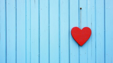 Red heart hanging on a blue wooden wall. Symbol of love and Valentine's Day.