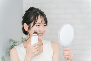 鏡を見ながらウォーターピーラーで角栓・毛穴ケアをするアジア人女性
