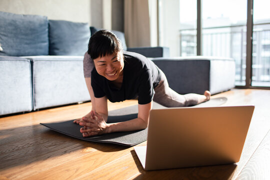 Asian woman stretching on yoga mat at home