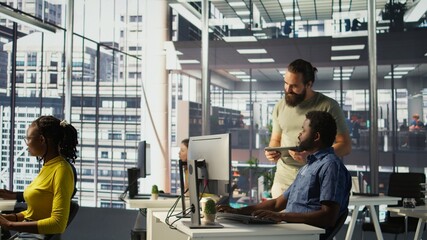 Manager coming to check on IT employee at office desk testing and deploying programs and systems....
