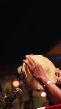 hands playing tambourine instrument at outdoor samba concert