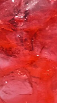 slow motion of ice cubes in cold red cocktail drink. beverage closeup, macro