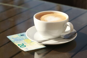 Tasty hot coffee and payment for order on table, closeup. Leave tip