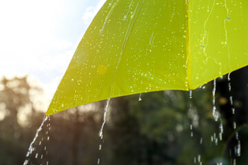 Open yellow umbrella under pouring rain outdoors, closeup