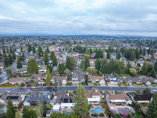 Aerial photographs over the Maidu Neighborhood in Roseville, California with green trees, streets, homes and a cloudy sky