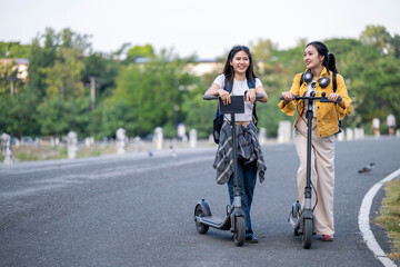 Fototapeta premium Two women riding scooters on a road