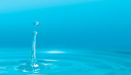 Water drops splashing on water surface forming waves against blue background