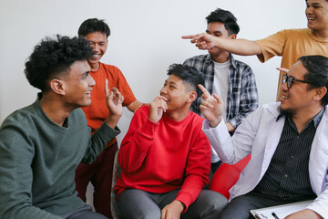 Portrait Of Multi Racial Group Laughing While Pointing To Friends During Therapy Session