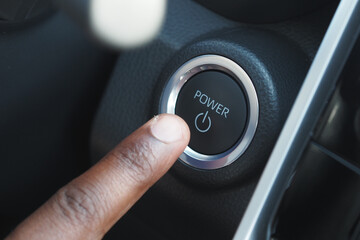 Hand pressing power button inside a car for ignition