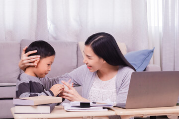 Obraz premium Happy single Asian mom drinks dairy milk from cute son hugging and kissing preschool boy bonding motherhood relationship, Asian freelancer woman remote working using modern technology laptop at home