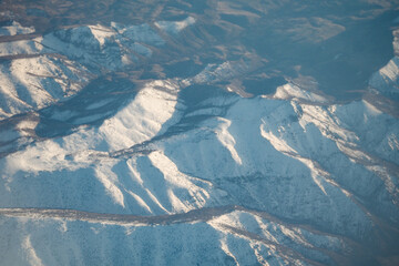 Snow-covered mountain range under clear sky in winter sunlight