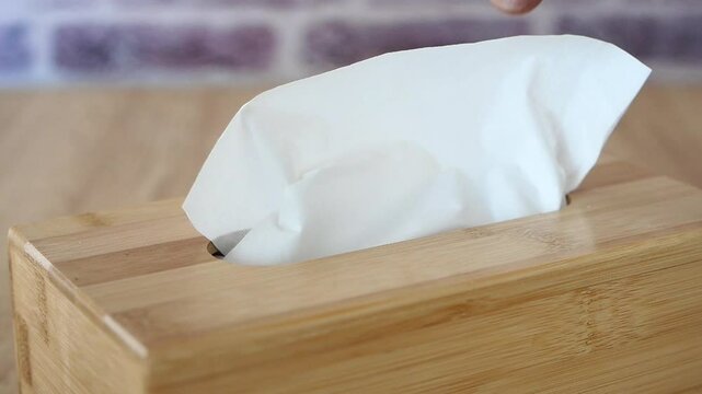 Tissue box with tissue poking out on a wooden table