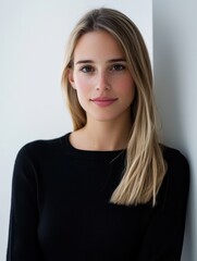 Fototapeta premium Young woman with straight blonde hair in a black long-sleeved shirt looking at the camera
