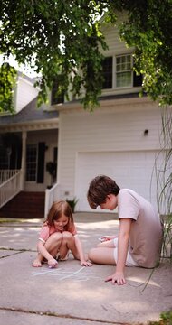 Barefoot Children Playing Tic-Tac-Toe with Chalk on Driveway &ndash; Fun Outdoor Summer Activity in Suburban Neighborhood. Carefree Summer Days