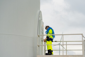 Worker performing maintenance on wind turbine in a renewable energy site during cloudy weather