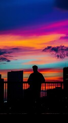 Obraz premium A man is standing on a bridge looking out over a city at a beautiful sunset
