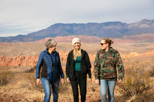 Three adult women hiking together in a desert landscape on a warm winter day. Enjoying the sun and the great outdoors while exercising and staying active