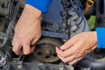 auto mechanic installing timing , hands Auto mechanic changes the timing belt in the car, close-up