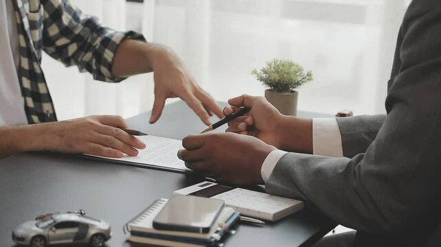 Car insurance documents or rental concept. A car broker helps his customers and explains the details of car contacts. Car keys. Buy or sell, sign.