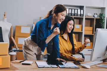 Asian SME business women use laptop computer checking customer order online shipping boxes at home....