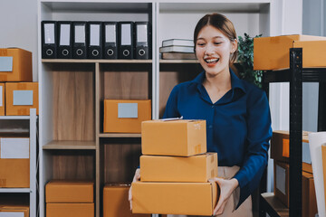 Asian SME business women use laptop computer checking customer order online shipping boxes at home....