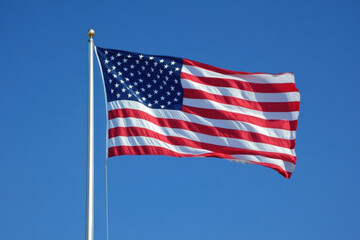 Obraz premium American flag flies in the wind against clear blue sky.