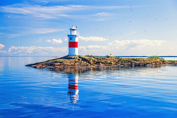 Lighthouse on a skerry with reflections in the calm water