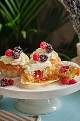 Cupcakes with vanilla cream and berries. Blue background, side view