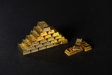 pyramid of shiny gold bars on a dark background, symbolizing wealth, investment, financial...