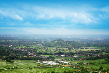Fototapeta premium Lush green landscape with distant hills and cloudy sky during daytime