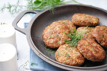 Frying pan with cutlets and dill on blue grunge table in kitchen
