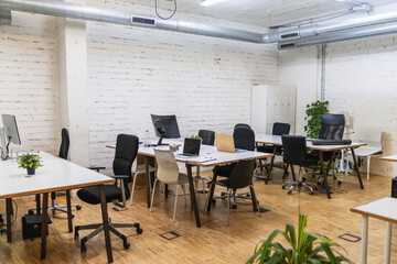 Coworking open space with nobody working, laptops and computers on desks
