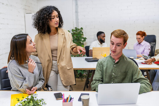 Managers coaching employee using laptop in coworking space