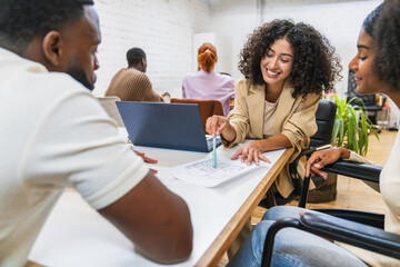 Smiling architect presenting blueprint to diverse colleagues in coworking space