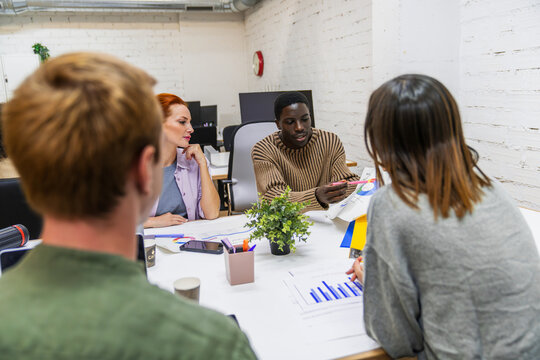 Marketing professionals discussing charts in coworking space