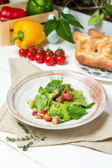 Salad of avocado, cherry tomatoes and lettuce in a plate on a serving table