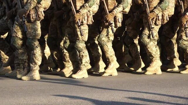 Soldiers with weapons are marching out of step,rehearsal.Movement is not synchronized.