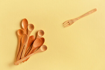 Different wooden spoons and fork on color background. Concept of uniqueness