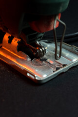 green jigsaw for cutting wood and metal for construction work in red light	