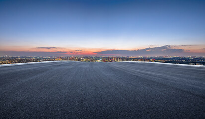 Fototapeta premium Empty asphalt road with modern cityscape at sunset